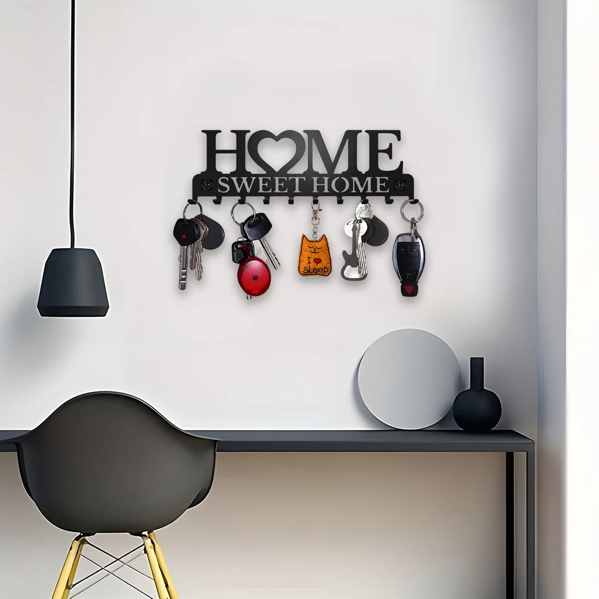 رف حائط أسود مطفي يعرض مفاتيح متنوعة ولوح خشبي مكتوب عليه "HOME SWEET HOME"