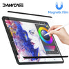 A hand writes on a tablet screen protected by a magnetic film, displaying colorful artwork.