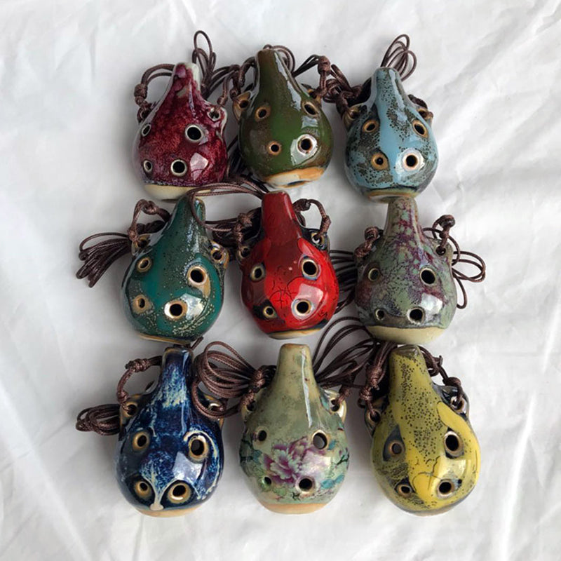 A collection of handcrafted ceramic pendant ocarinas with six holes in various earthy and vibrant colors.