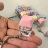 A hand holds a clear plastic keychain featuring multiple pastel colored mechanical keyboard fidget cubes.