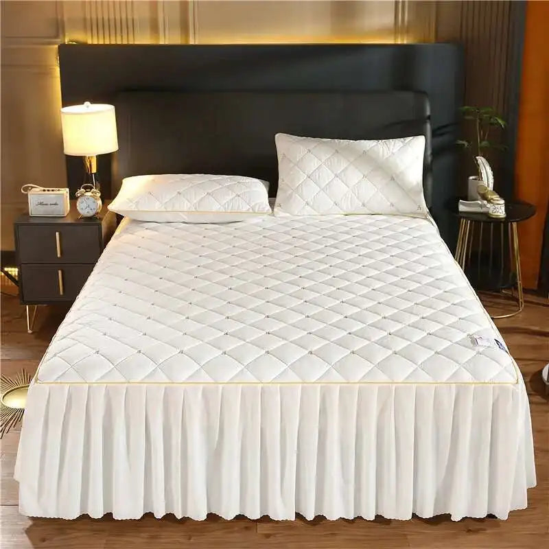 White quilted bed skirt with a diamond pattern and a white quilted duvet on a bed.