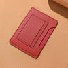 A pink leather passport holder with card slots resting on a beige surface.