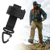 A man wearing a gray jacket and tan pants stands on rocky terrain next to a black nylon glove hook with an adjustable clip.