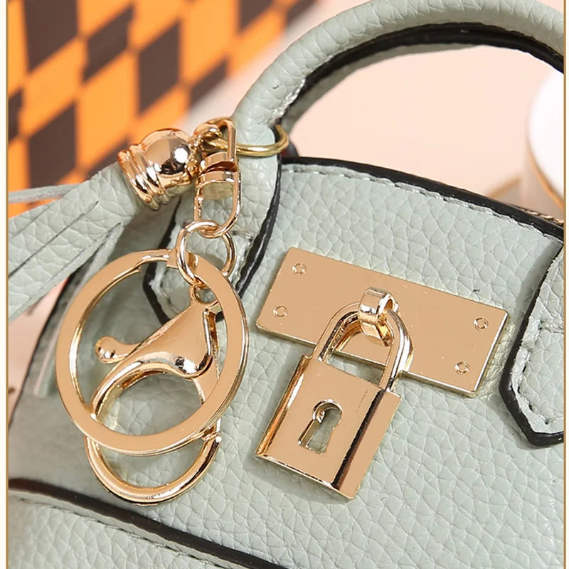 A gold-toned keychain featuring a padlock charm attached to a light mint green PU leather case.