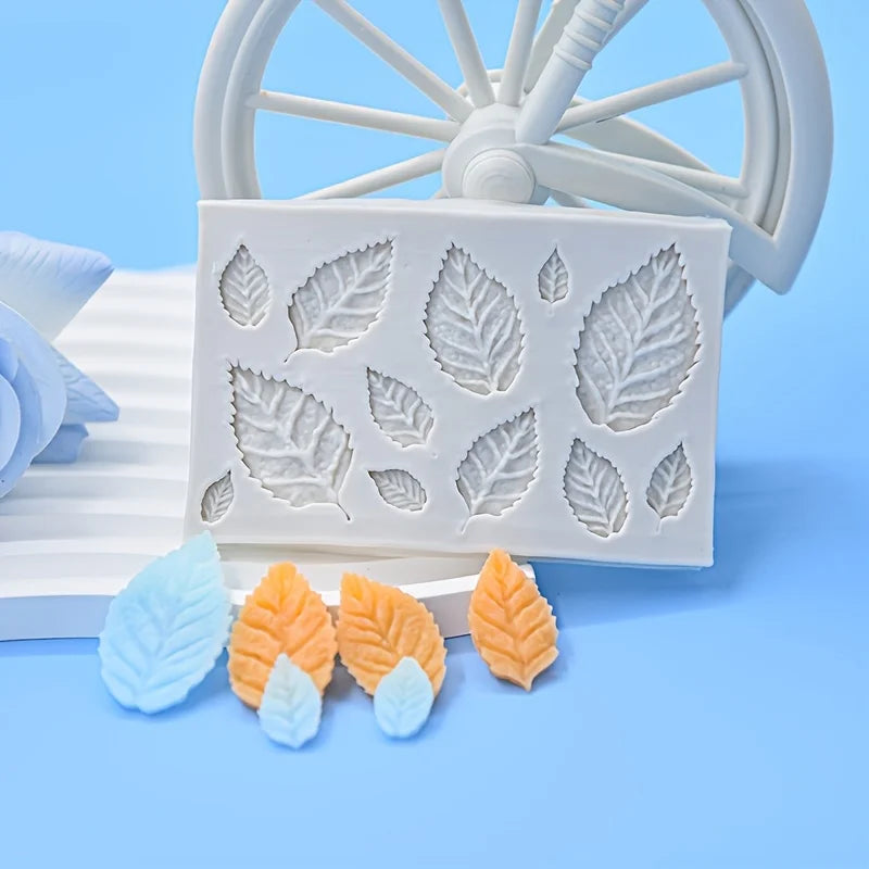 White silicone mold with rose leaf designs for candle making and crafting placed next to a white wooden wheel.