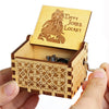 A hand holds an open wooden music box with a lid featuring an engraved design of a figure and the text Davy Jones Locket.