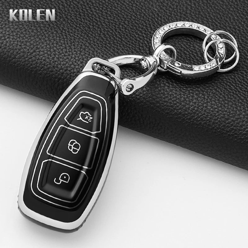A silver key fob attached to a chain is displayed on a black leather surface.