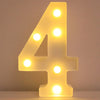 A glowing yellow LED letter night light shaped like the number four, illuminating a white surface.