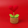 Handcrafted crochet heart plant with a red heart flower growing in a brown pot.