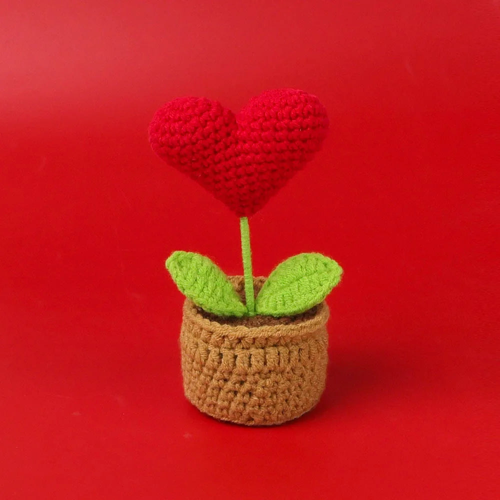 Handcrafted crochet heart plant with a red heart flower growing in a brown pot.