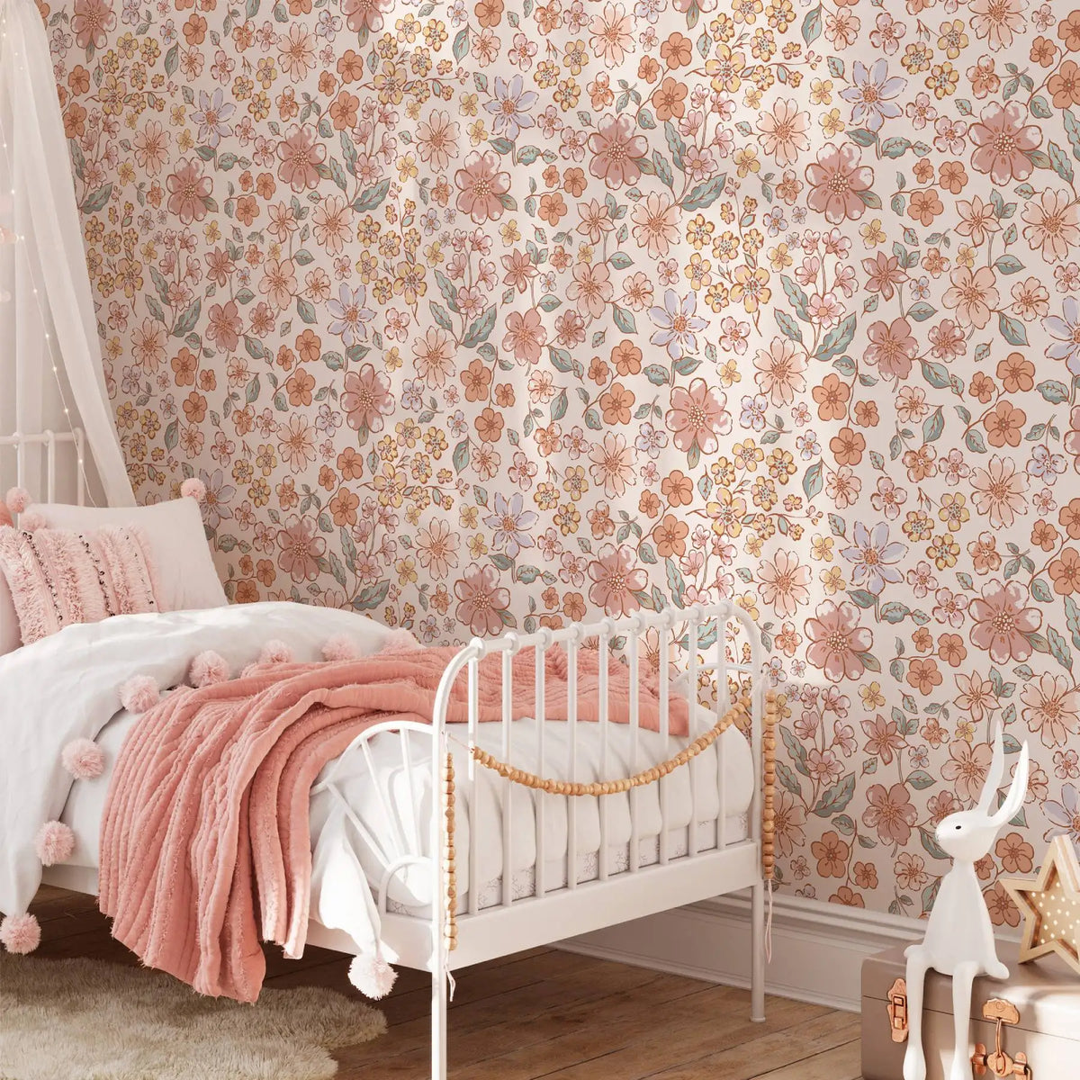 A white wooden bed decorated with pink and peach floral wallpaper and a soft pink blanket.