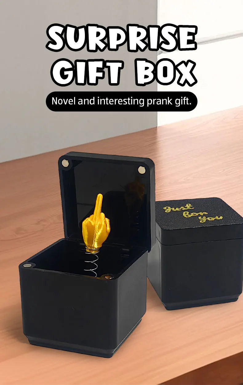 A black surprise gift box with an open lid revealing a golden middle finger hand.