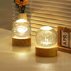 A glowing crystal ball night light with a white deer silhouette is displayed on a wooden base.