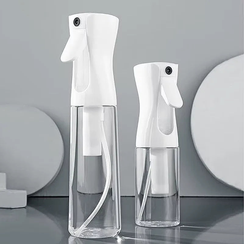 Two clear glass bottles of a white fine mist spray bottle with a doe-foot applicator on a gray surface.
