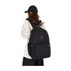 A person wearing a black baseball cap is shown carrying an urban nylon backpack for everyday commute.