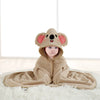 A baby wearing a tan hooded towel with an elephant face design lying on a white surface.