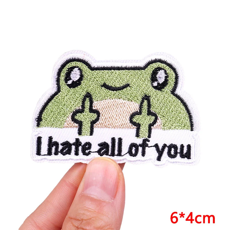 An embroidered patch featuring a smiling green frog with the text I hate all of you