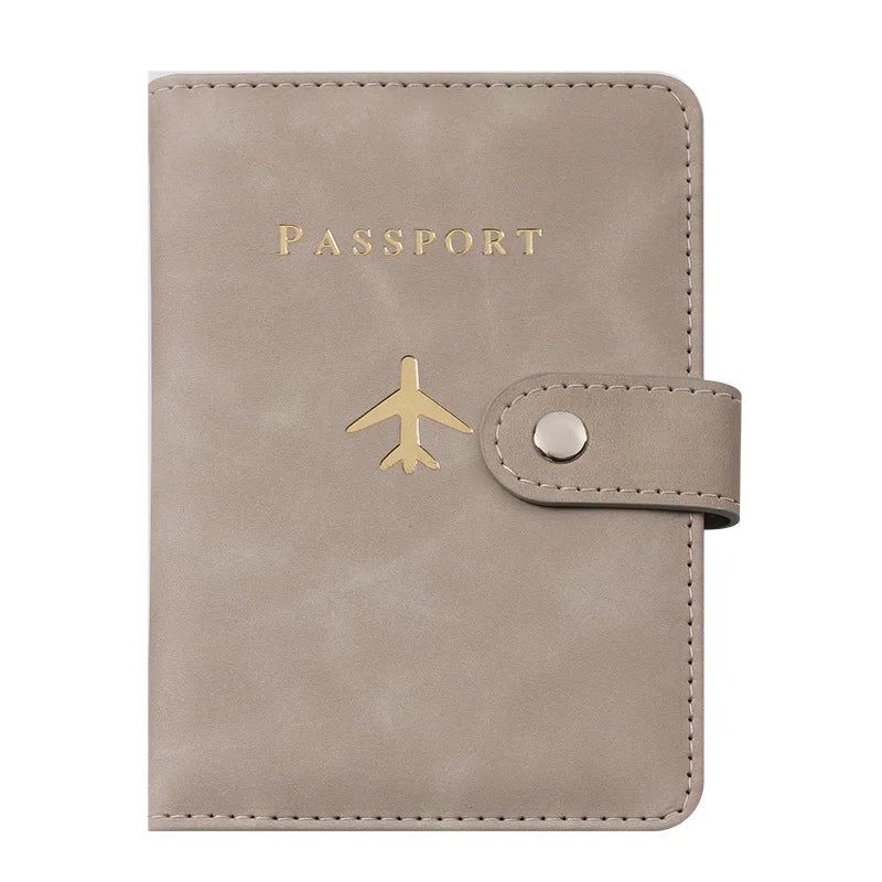 Porte-passeport en cuir beige avec lettres dorées et une sangle en cuir.
