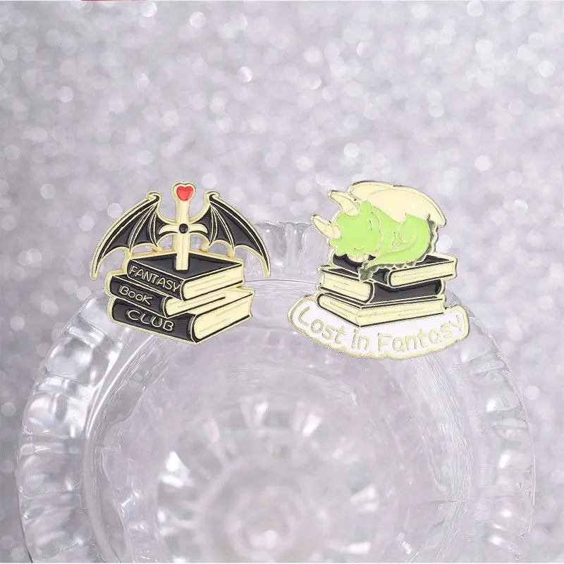 A set of enamel pins featuring fantasy book club and lost in fantasy themed designs.