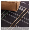 A close-up view of a brown velvet blanket placed on a dark play mat with white and gold lines.