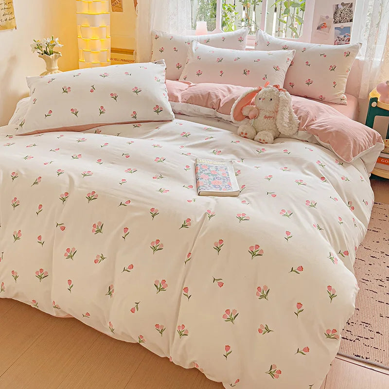 A floral duvet cover set in white with pink accents, featuring a flat sheet and pillows.