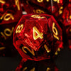 A single red resin polyhedral die with gold numbers is displayed on a reflective surface.