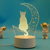 A clear acrylic silhouette of a cat inside a crescent moon shape, illuminated by LED light.