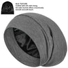 A gray silk satin sleep bonnet rolled up, showing the smooth texture and lining.