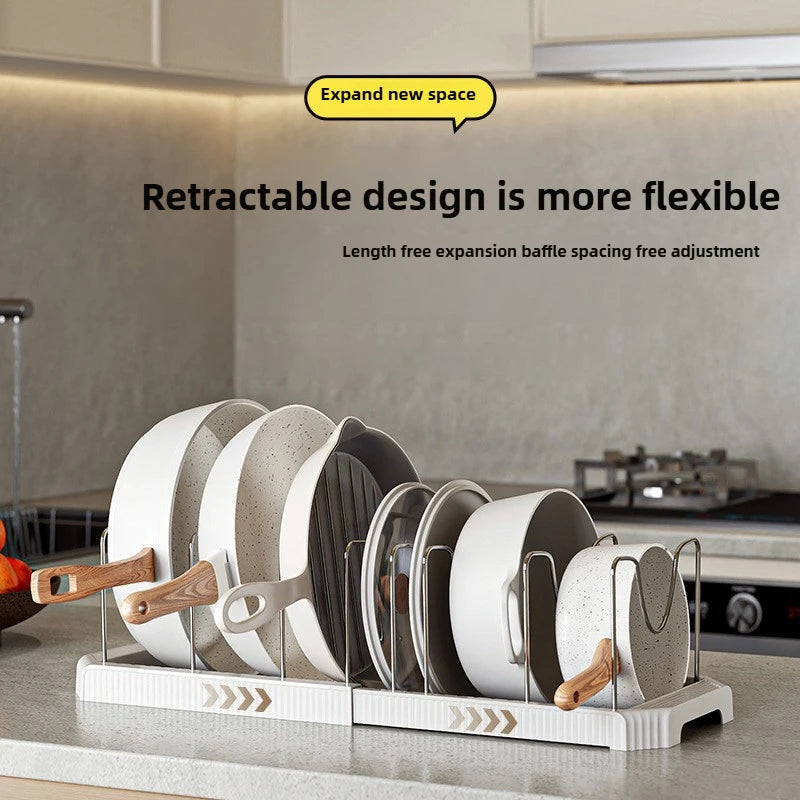 A white organizer rack holds various black and gray pots and pans for flexible storage.