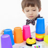 A child is holding a colorful stacking cup set and activity cards for early learning.