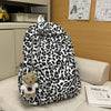 A leopard print nylon backpack with multiple pockets resting on a light-colored surface.