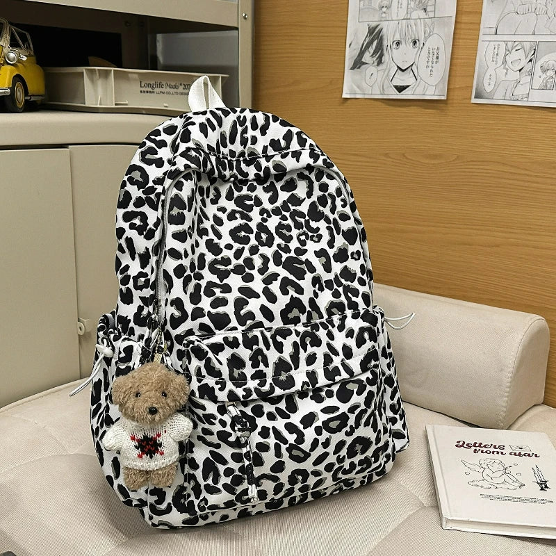 A leopard print nylon backpack with multiple pockets resting on a light-colored surface.