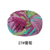 A ball of purple and green chunky acrylic yarn for knitting and crochet