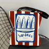 A canvas tote bag featuring a blue and white illustration of sardines in a rectangular frame on a striped background.