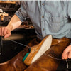 A person is using a waxed nylon thread to sew or repair leather, demonstrating the thread's use for heavy-duty work.