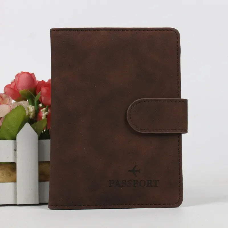 Un porte-passeport en cuir marron foncé à côté d'un petit vase de fleurs roses et rouges.