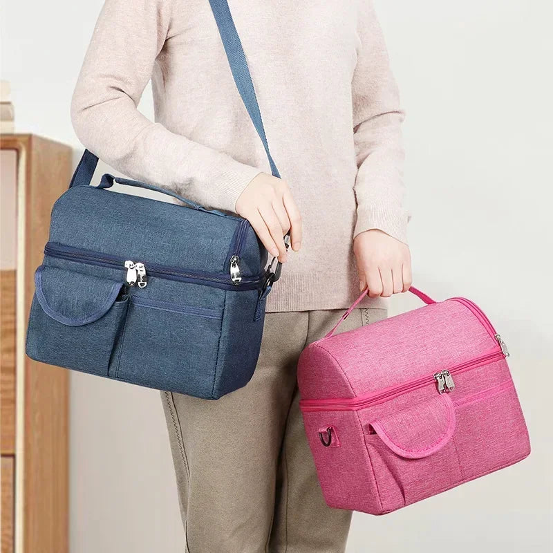 A person is holding a navy blue insulated lunch bag and a pink insulated lunch bag.