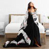 A woman is lying on a bed with a black and white vintage art clown coral fleece throw blanket draped over her.