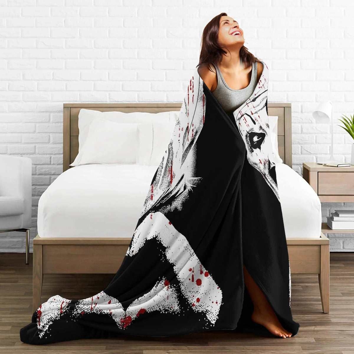 A woman is lying on a bed with a black and white vintage art clown coral fleece throw blanket draped over her.