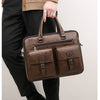 Braunes Herren-Business-Etui aus Kunstleder, gehalten von einer Person in schwarzen Hosen und beigener Jacke.