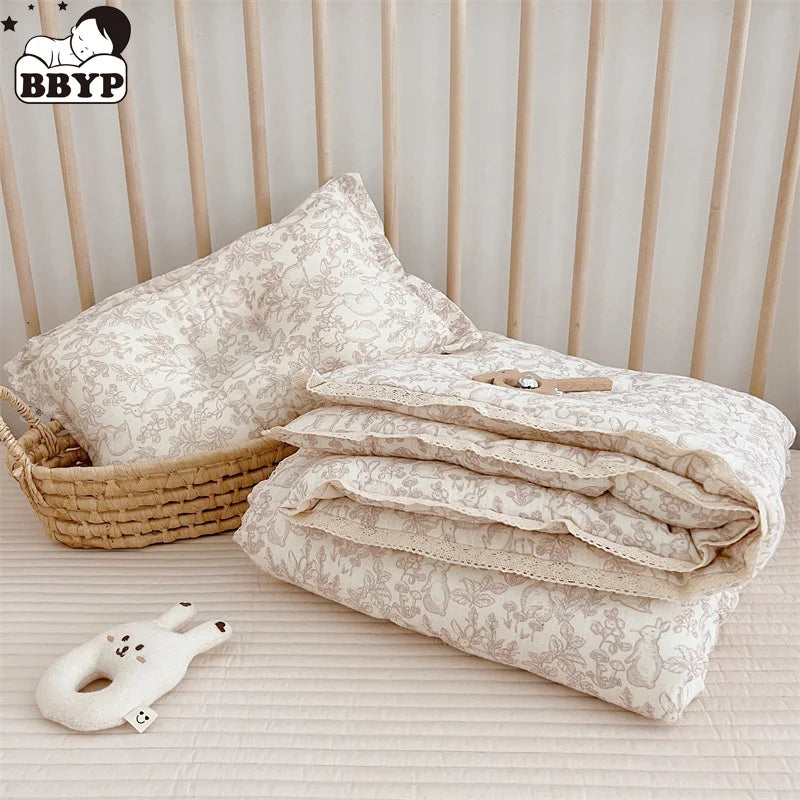 A stack of floral muslin baby blankets and a small white stuffed animal are displayed on a light surface.