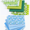 A stack of cotton fabric squares featuring various floral dot patterns in shades of green and blue.