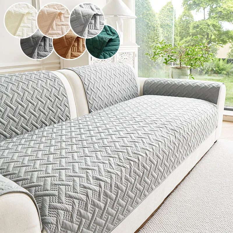 A gray quilted anti-slip sofa cushion displayed on a white sofa with decorative fabric accents.