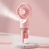 A pink portable USB rechargeable mist fan with a clear container is displayed on a white speckled surface.