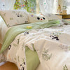 A light green panda print comforter with lace trim and a white stuffed animal pillow on a bed.