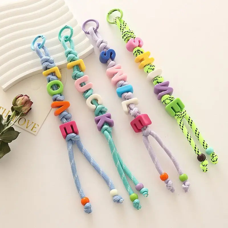 Ten alphabet letter beads in various colors and shapes strung on threads for DIY jewelry making