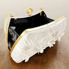 A white pearl embroidered evening clutch with a gold chain and black velvet lining.