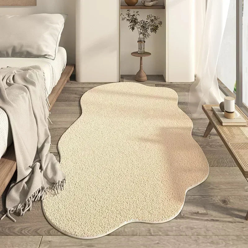 A cream colored irregular area rug with a plush soft texture placed on a light wood floor.