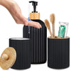 A hand is dispensing liquid from a black bottle dispenser, next to holders for cotton and toothbrushes.