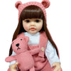 A lifelike silicone baby doll with long dark hair wearing a pink knitted outfit and a matching headband.